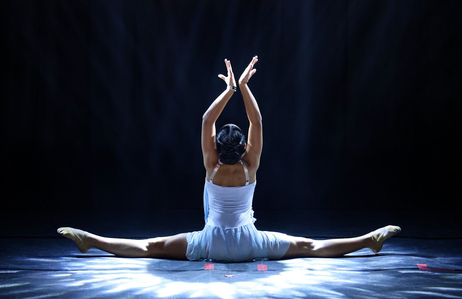 Bailarina da EIDD em grand écart sob luz azul