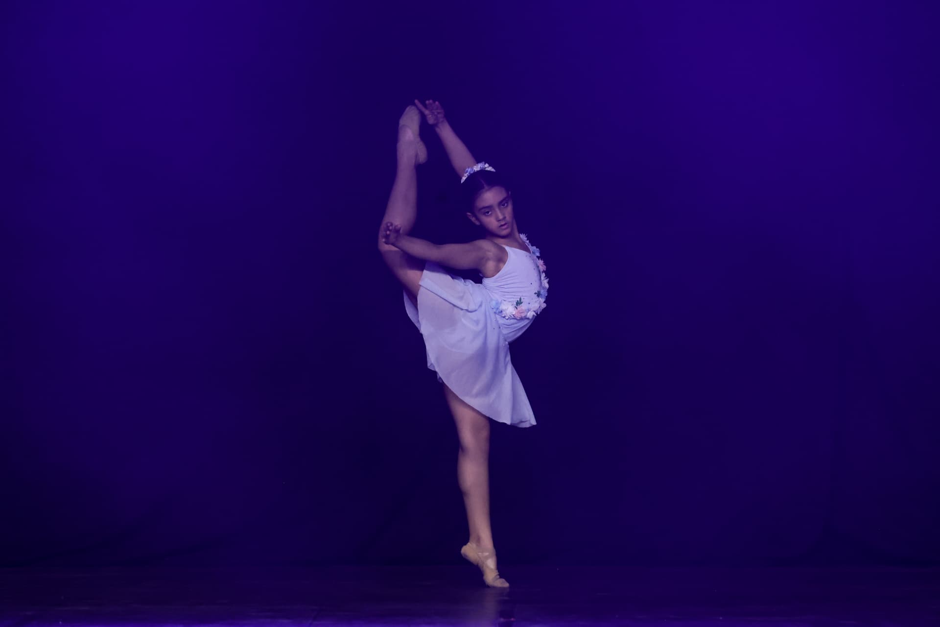 Bailarina em pose de arabesque com iluminação lilás